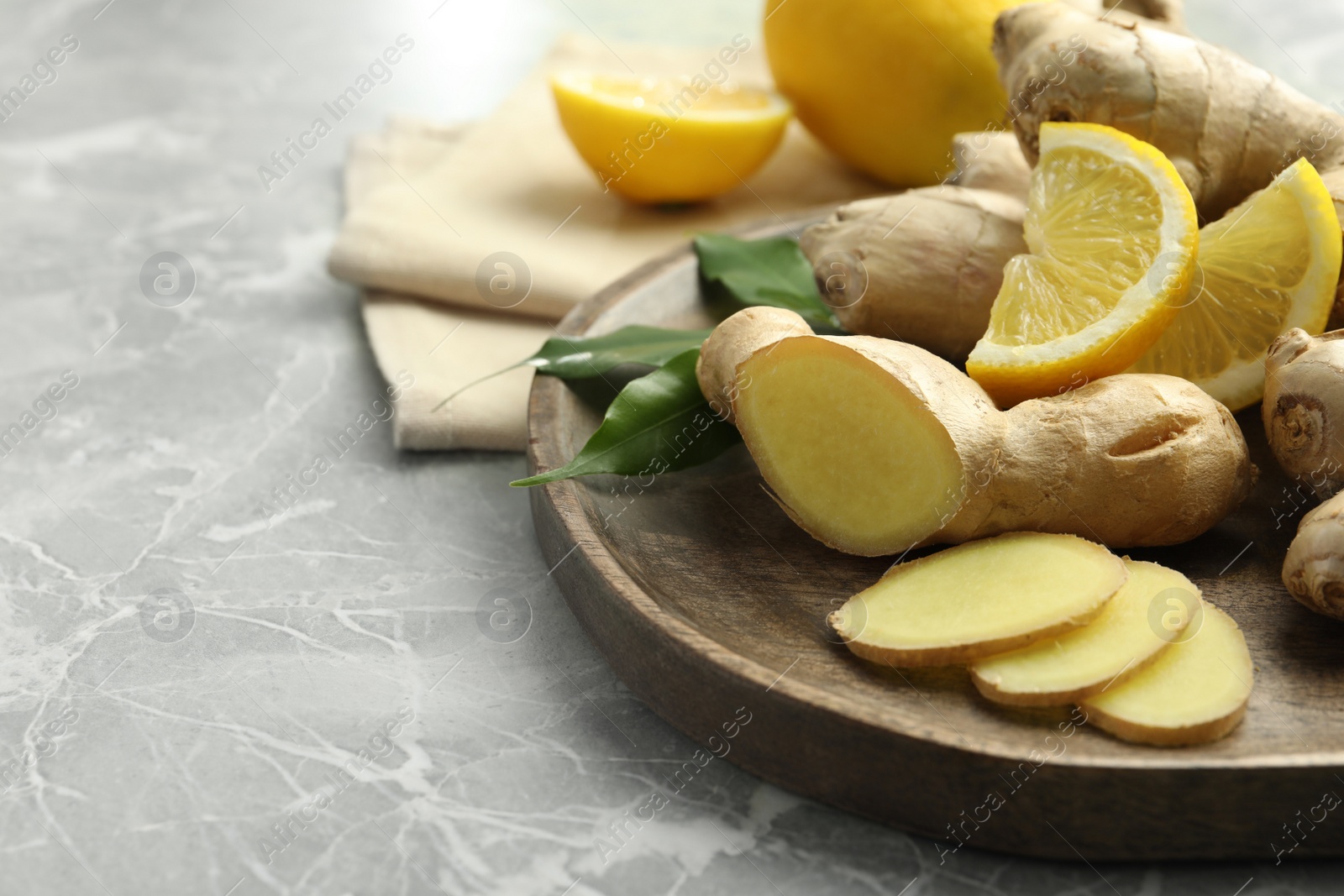 Photo of Fresh lemon and ginger on grey marble table, closeup. Space for text