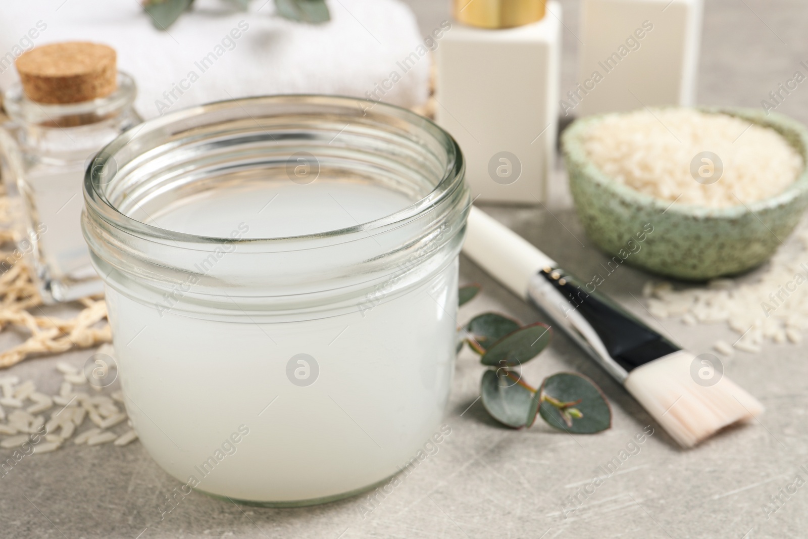 Photo of Homemade natural rice water and cosmetic products on light grey table