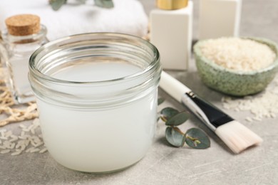 Photo of Homemade natural rice water and cosmetic products on light grey table