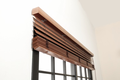 Modern window with stylish wooden blinds indoors. Space for text