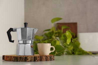 Photo of Ceramic cup and moka pot on light countertop in kitchen, space for text