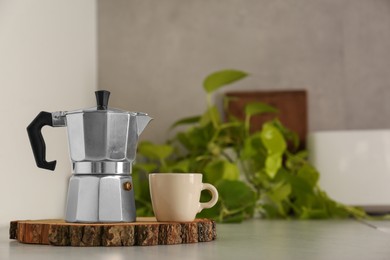 Ceramic cup and moka pot on light countertop in kitchen, space for text