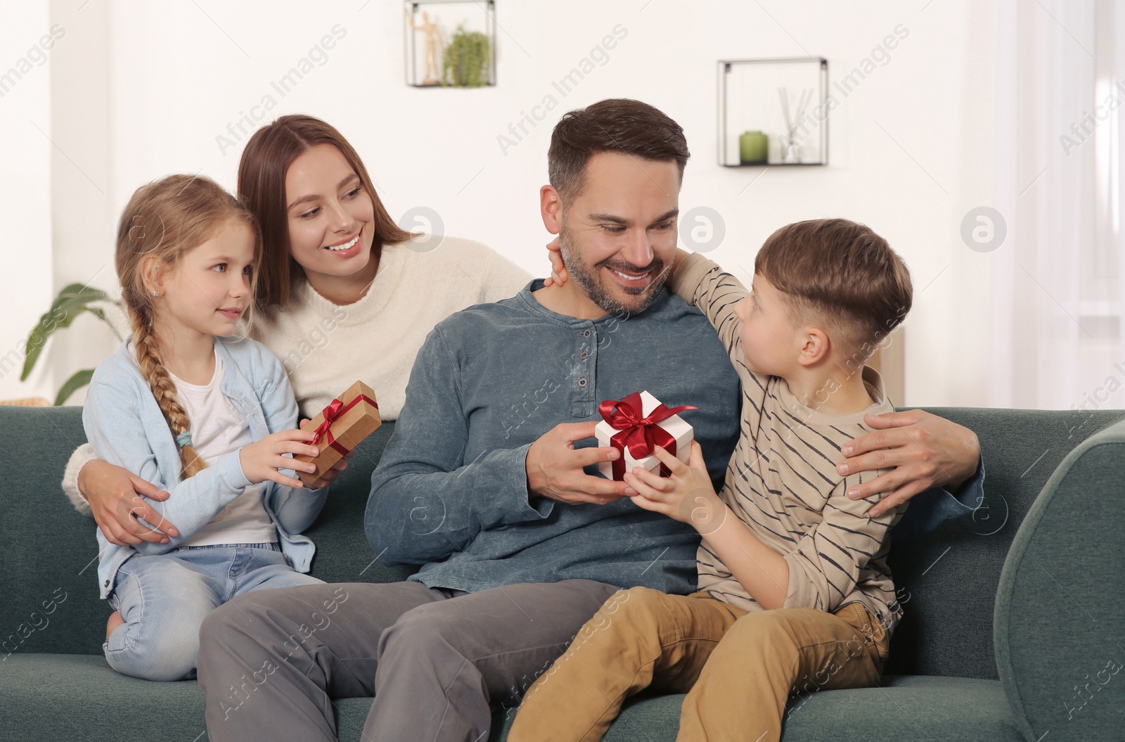 Photo of Little children presenting their parents with gifts at home