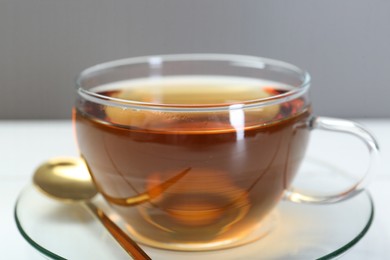 Photo of Glass cup of tea on white table, closeup