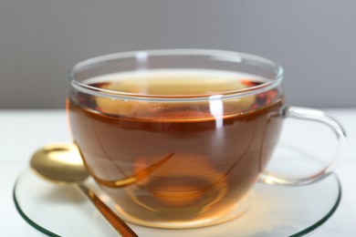 Glass cup of tea on white table, closeup