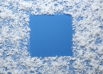 Photo of Frame made of snow on blue background, top view with space for text. Winter season