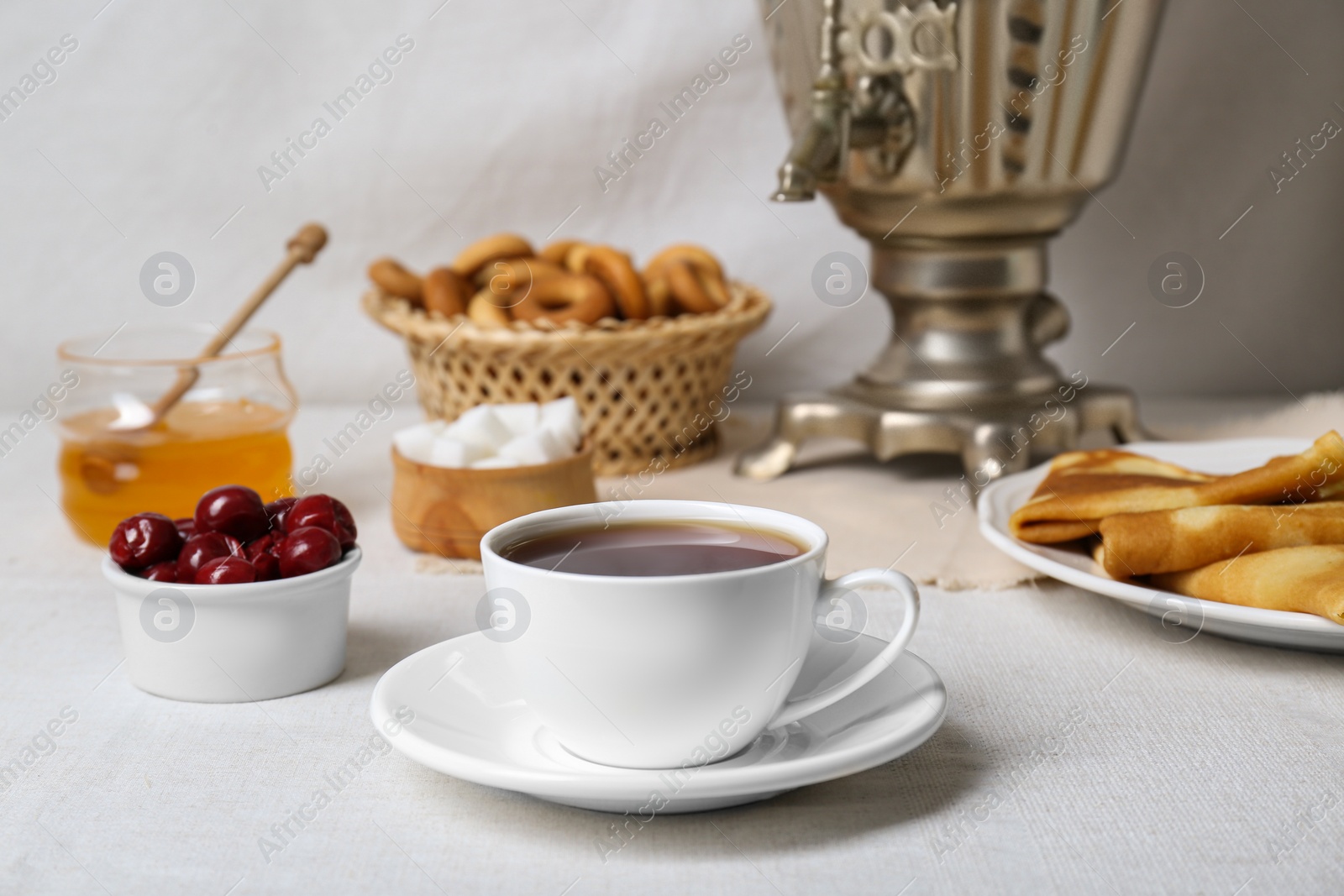 Photo of Aromatic tea, traditional Russian samovar and treats on table