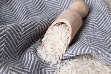 Photo of Raw basmati rice in scoop on fabric, closeup