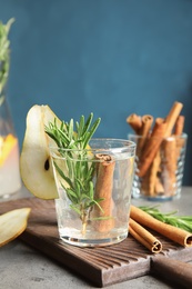 Tasty refreshing cocktail with rosemary and cinnamon on table