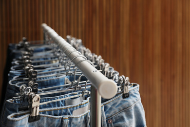 Rack with different jeans on wooden background, closeup