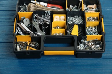 Photo of Plastic box with different furniture fittings and tools on blue wooden table, above view