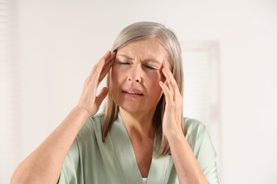 Photo of Menopause. Woman suffering from headache in bathroom