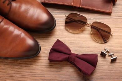 Photo of Flat lay composition with stylish burgundy bow tie on wooden background