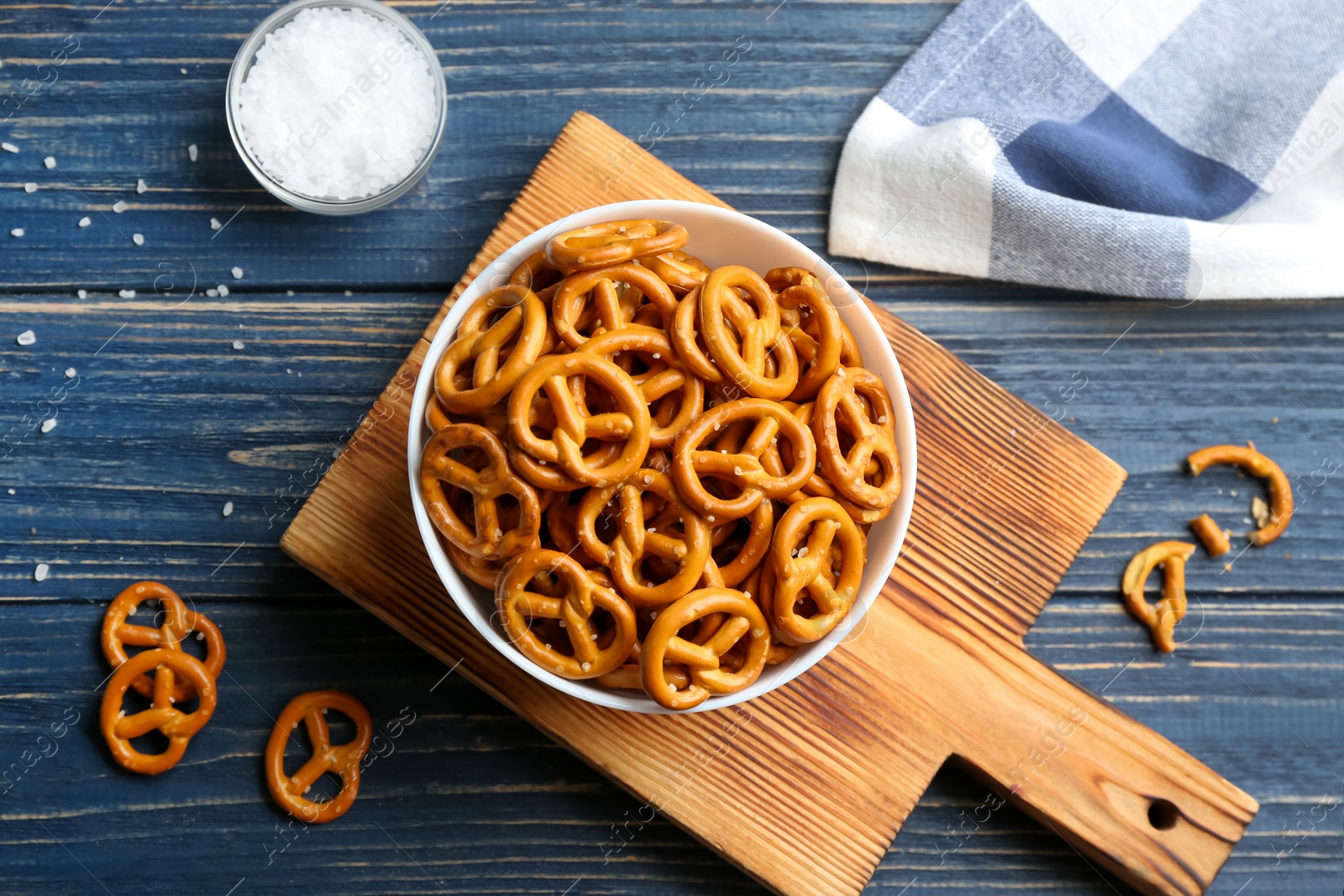 Photo of Delicious pretzel crackers on blue wooden table, flat lay