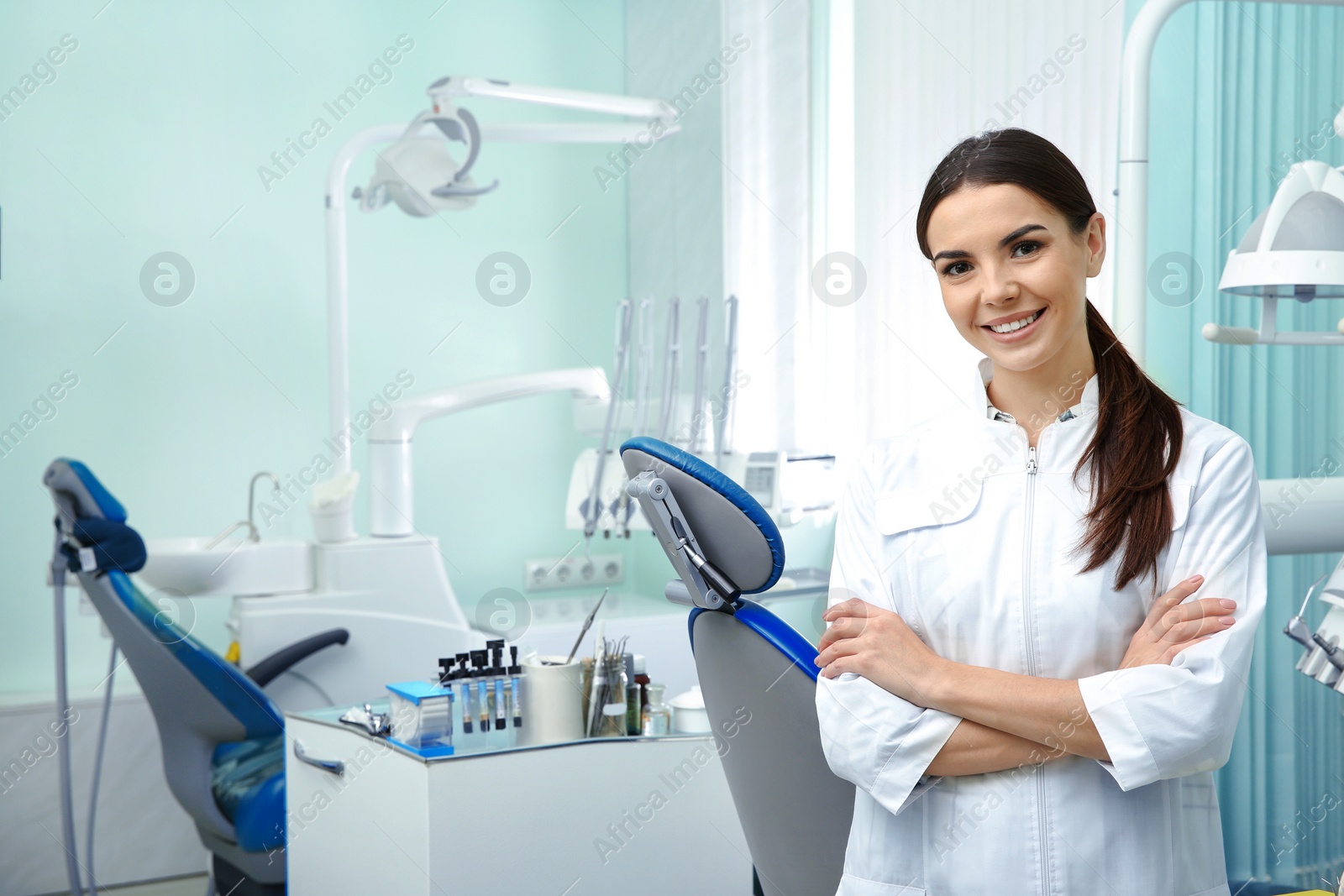 Photo of Young female dentist in white coat at workplace. Space for text