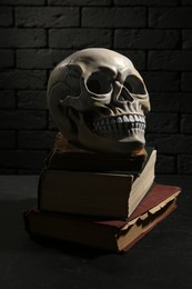 Human skull with books on black background