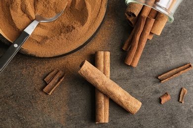 Photo of Aromatic cinnamon sticks and powder on grey background