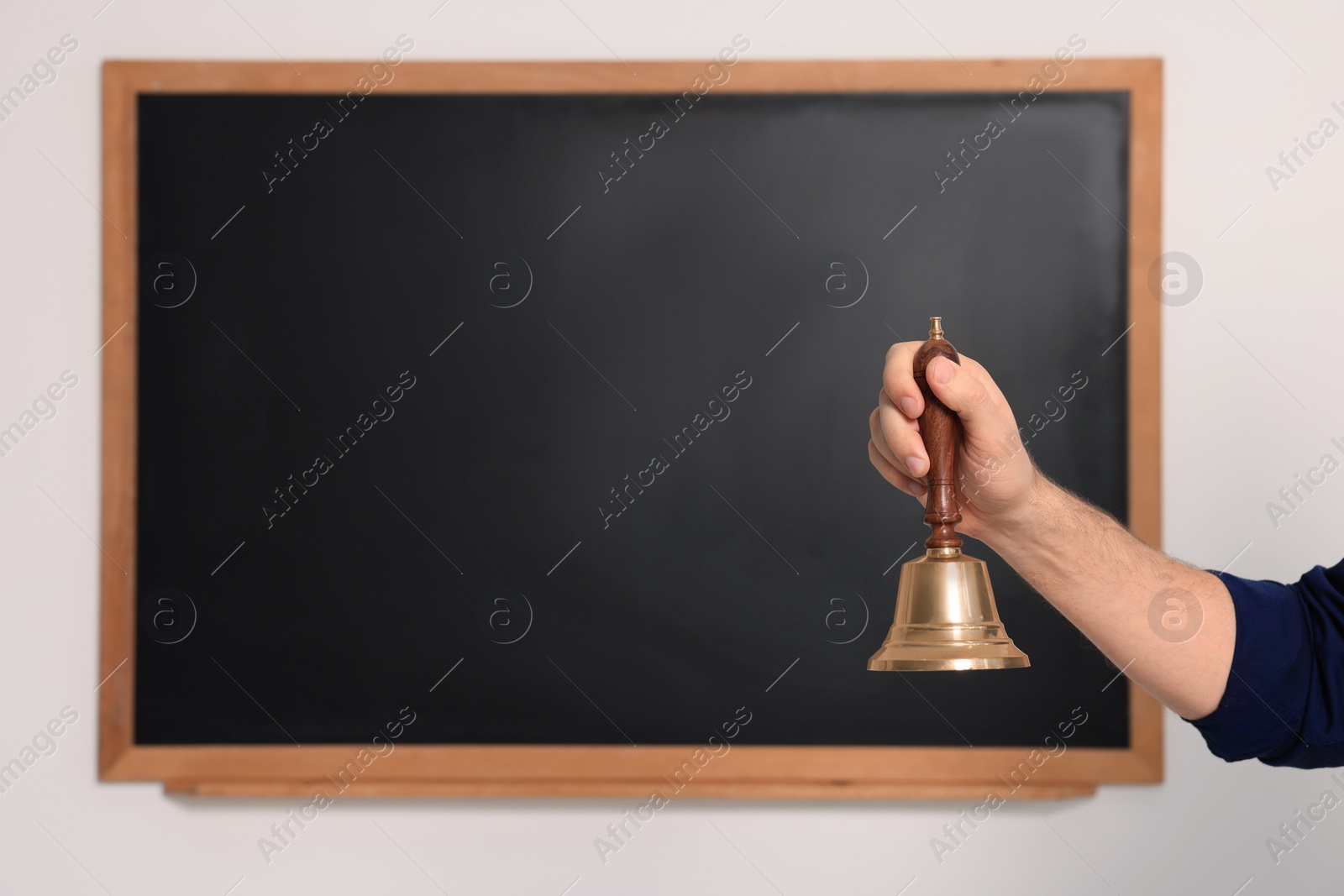 Photo of Teacher with school bell near black chalkboard, closeup. Space for text