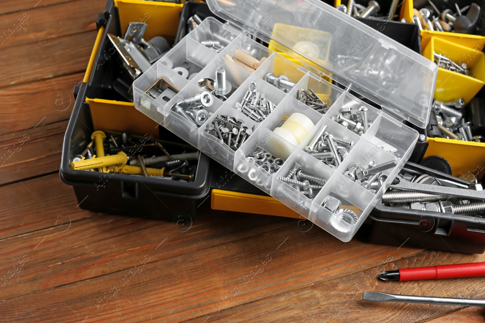 Photo of Boxes with different furniture fittings and tools on wooden table, closeup