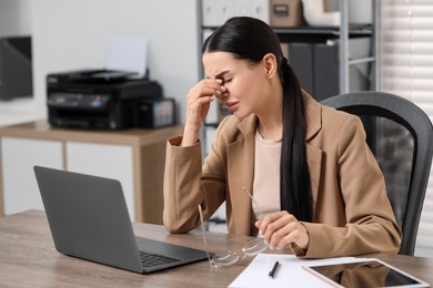 Photo of Woman suffering from headache at workplace in office