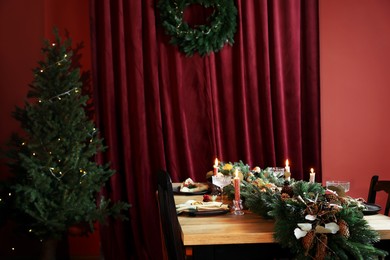 Photo of Dining table with burning candles and Christmas decor in stylish room. Interior design