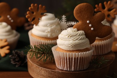 Tasty Christmas cupcake with gingerbread man and fir branches on wooden board