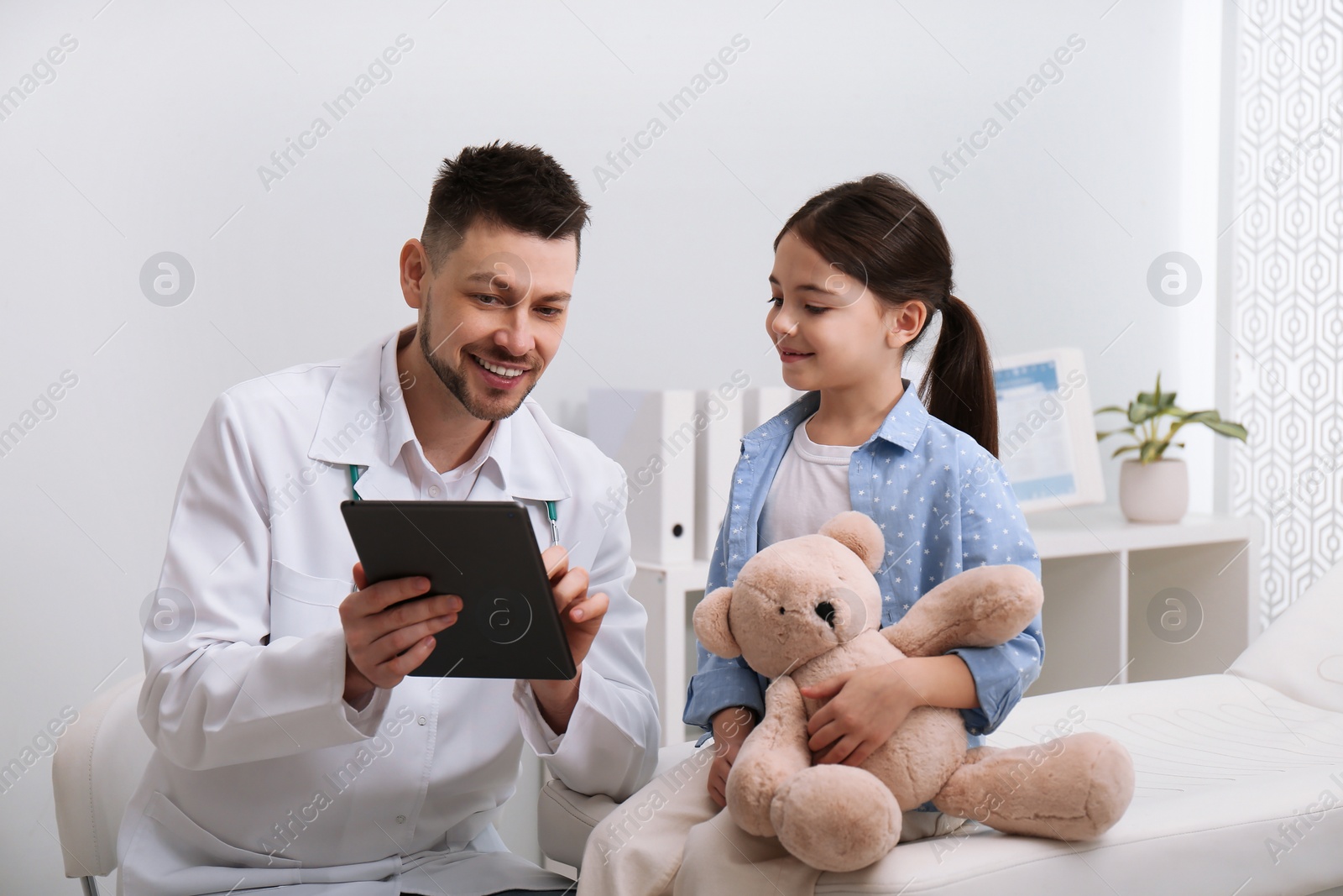 Photo of Pediatrician explaining physical examination result to little girl in hospital