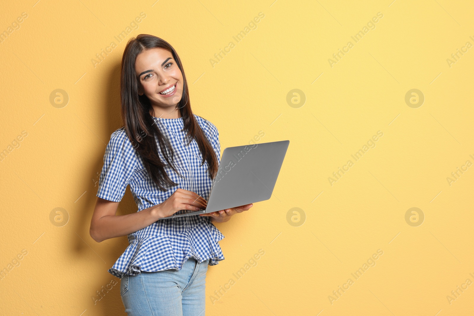 Photo of Young woman with modern laptop on color background