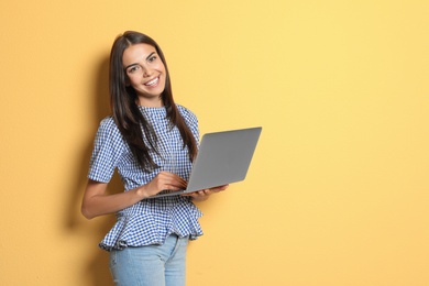 Young woman with modern laptop on color background