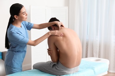 Photo of Orthopedist examining man's neck in clinic. Scoliosis treatment