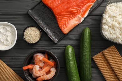 Photo of Making sushi rolls. Flat lay composition with ingredients on black wooden table