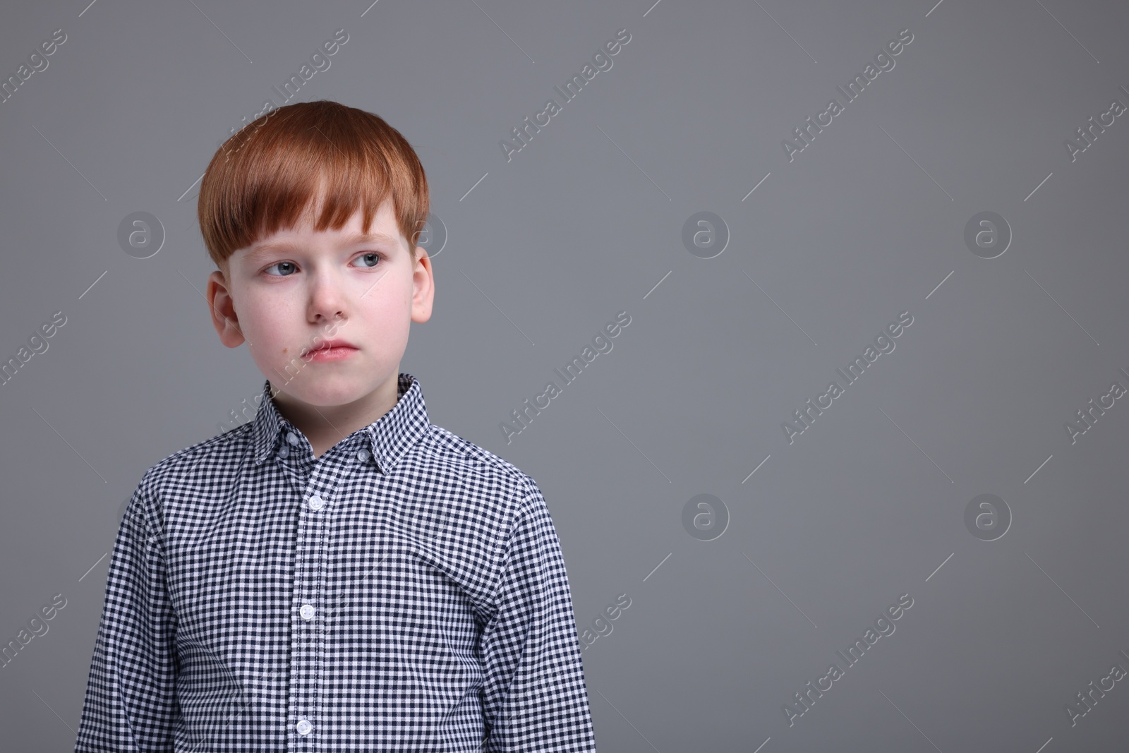 Photo of Portrait of sad little boy on grey background, space for text