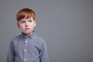 Photo of Portrait of sad little boy on grey background, space for text