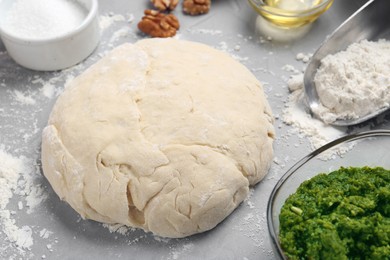 Photo of Making delicious pesto bread. Raw dough and ingredients on grey table, closeup