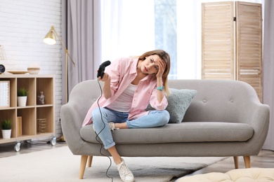 Photo of Emotional young woman playing video game at home