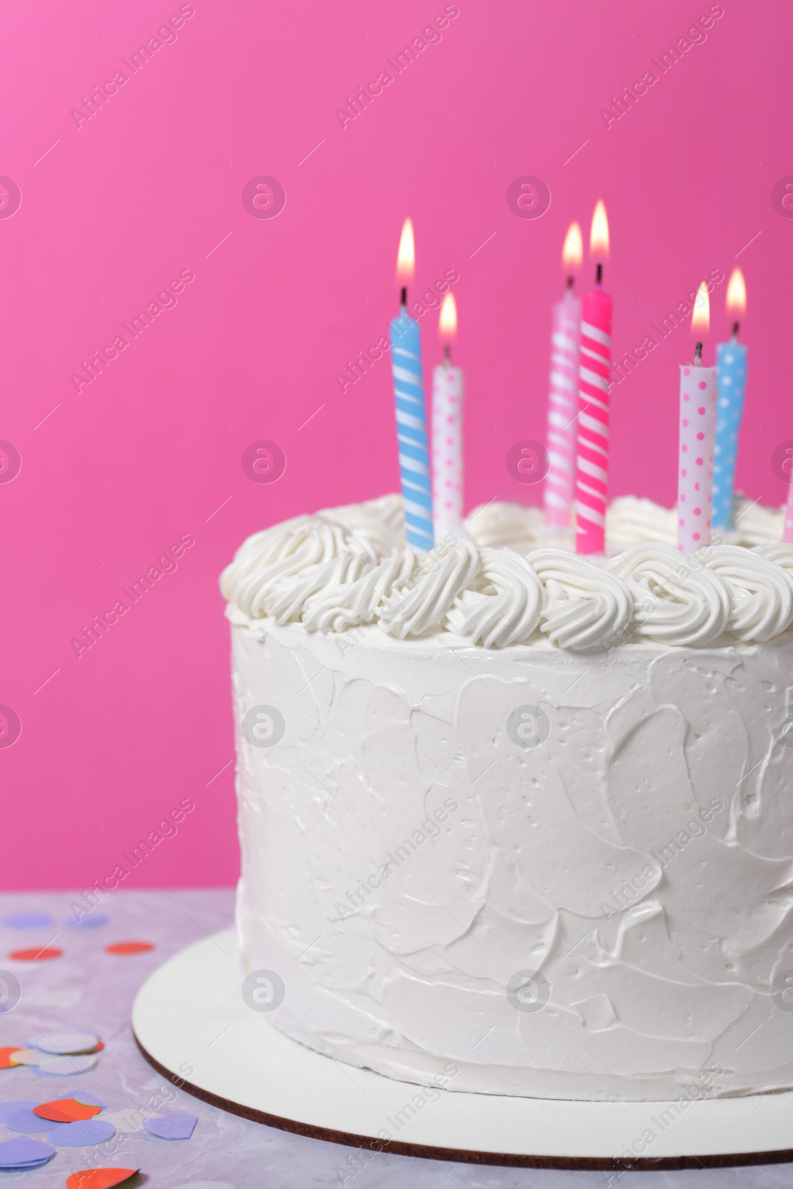 Photo of Delicious cake with cream and burning candles on grey table, closeup