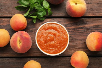 Photo of Apricot puree in bowl and fresh fruits on wooden table, flat lay