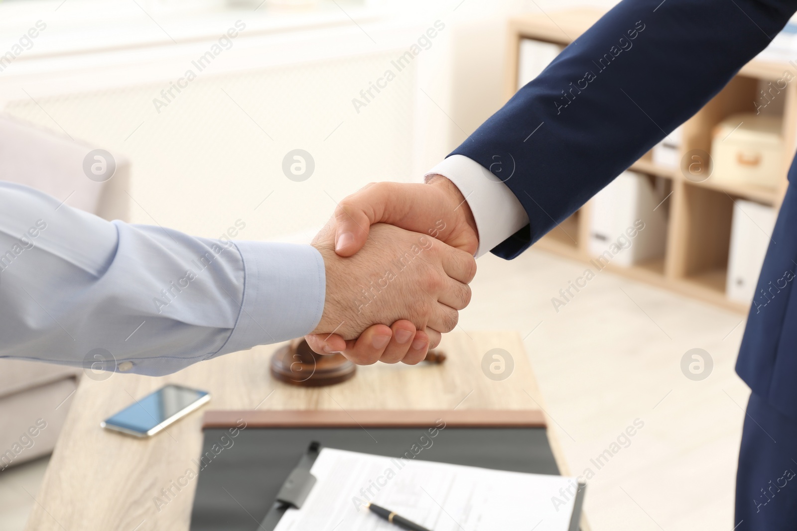 Photo of Lawyer handshaking with client over table in office, closeup