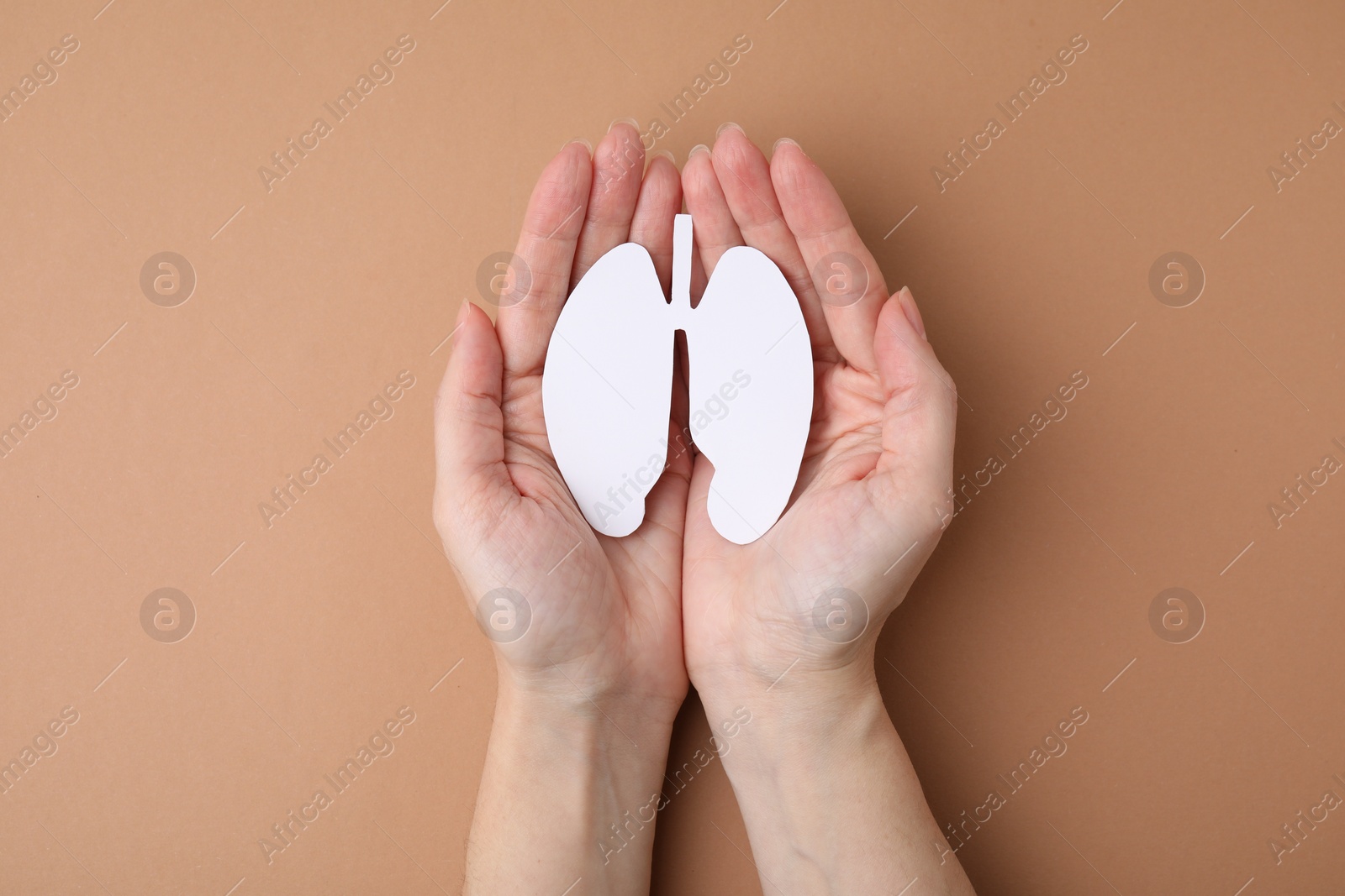 Photo of Quitting smoking concept. Woman holding paper lungs on beige background, top view