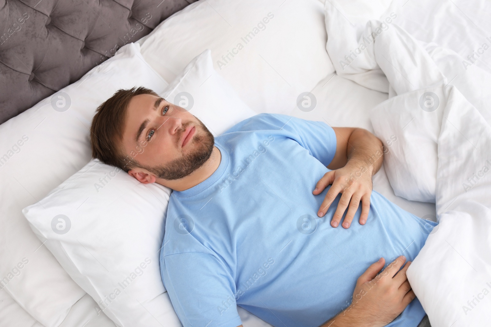 Photo of Young man lying in bed at home. Sleep disorder