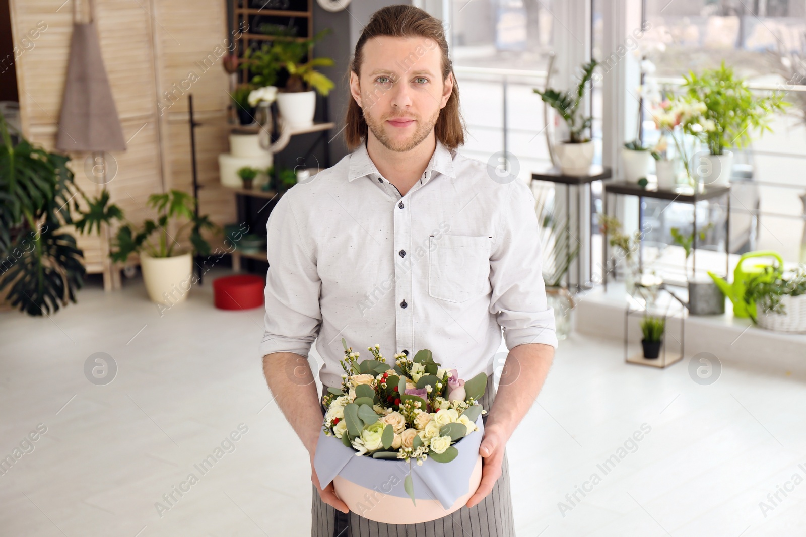 Photo of Male florist holding box with flowers at workplace