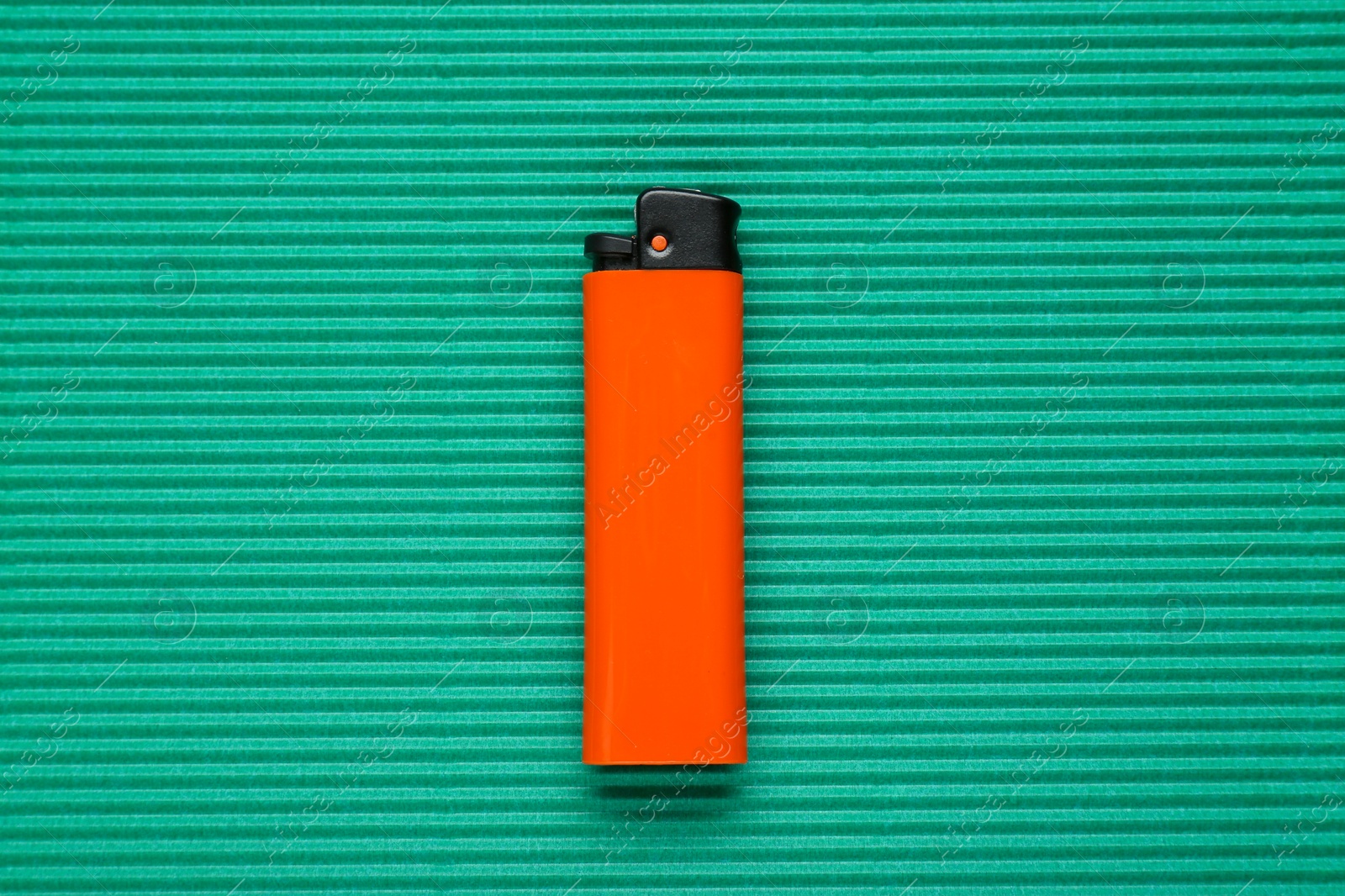 Photo of Stylish small pocket lighter on green corrugated fiberboard, top view