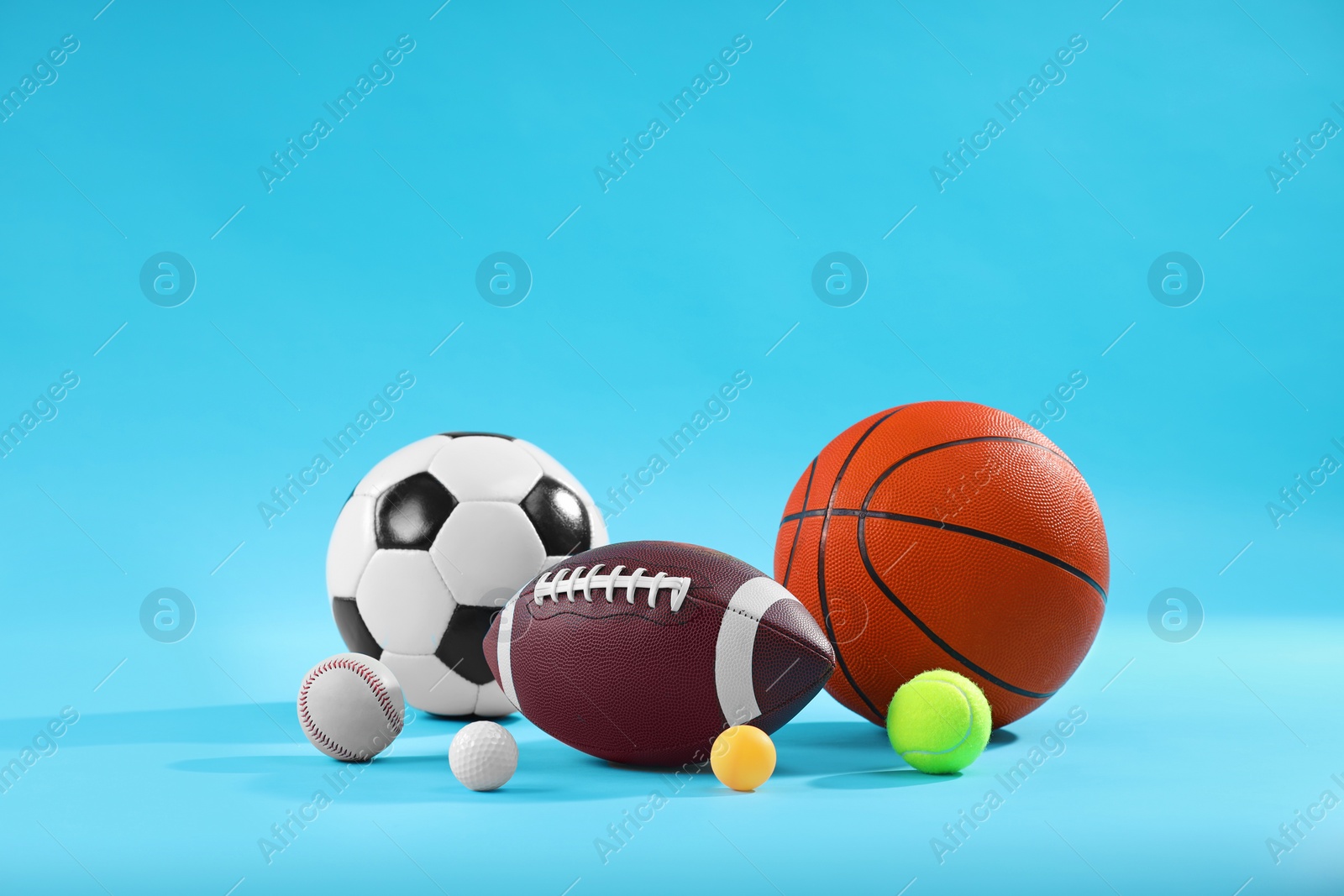 Photo of Many different sports balls on light blue background, space for text