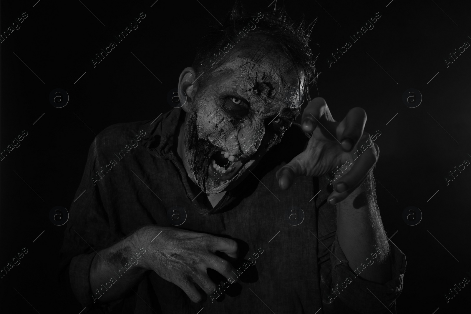 Photo of Scary zombie on dark background, black and white effect. Halloween monster