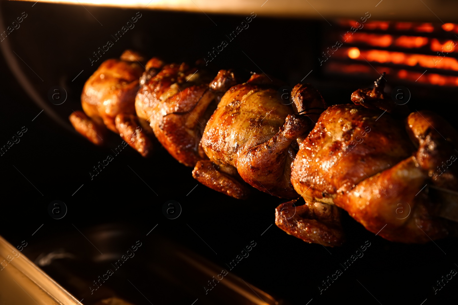 Photo of Grilling whole chickens in rotisserie machine, closeup