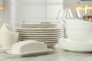 Clean plates, bowls, cups and glasses on white marble table in kitchen