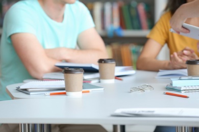 Photo of Young people studying at table in library, closeup