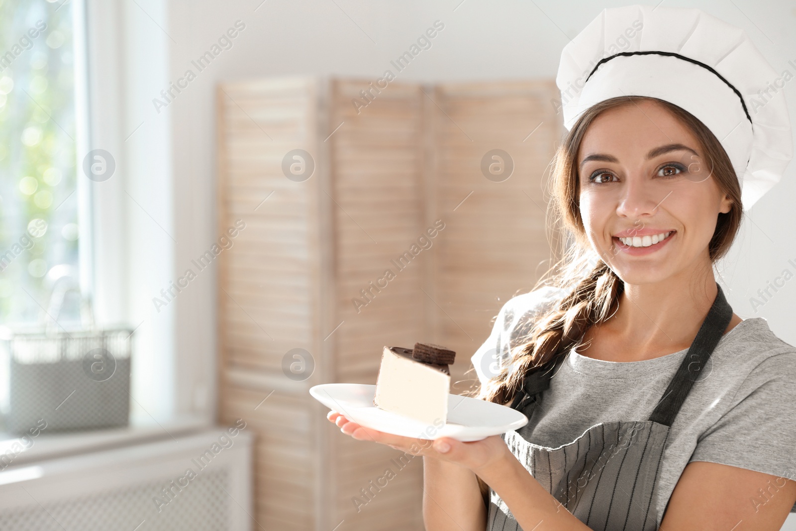 Photo of Professional female chef with plate of delicious dessert in kitchen