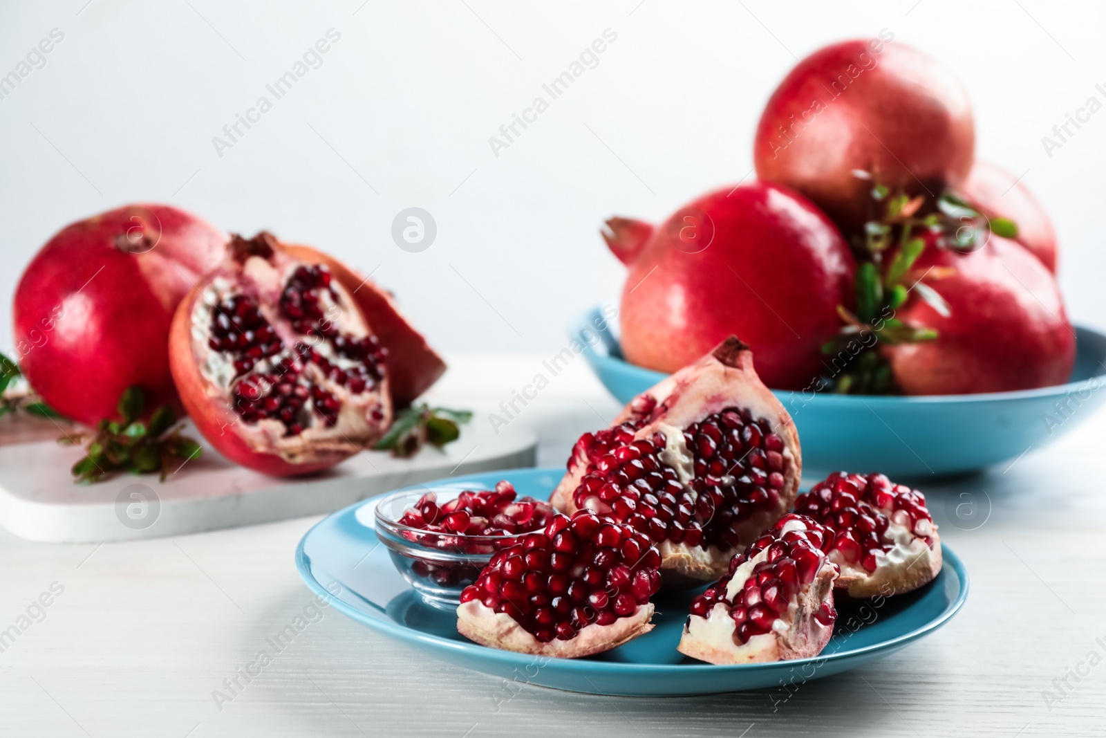 Photo of Delicious ripe pomegranates on white wooden table