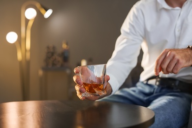 Photo of Man with glass of whiskey sitting at table, closeup. Space for text